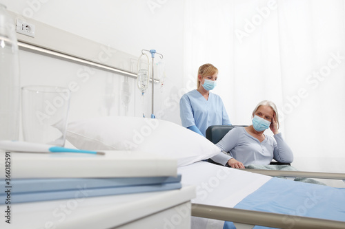 nurse take comfort elderly woman in wheelchair wearing surgical protective medical masks in hospital room, concept of isolation from corona virus covid 19