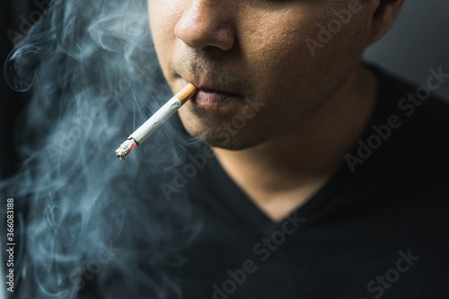 Close up young man smoking a cigarette darknest mood and tone.