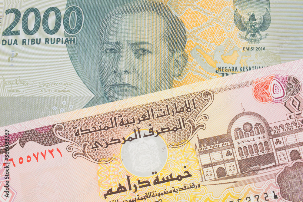 Fototapeta premium A macro image of a grey two thousand Indonesian rupiah bank note paired up with a colorful five dinar bank note from the United Arab Emirates. Shot close up in macro.