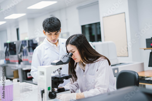 Two medical scientist working in Medical laboratory , young female scientist looking at microscope