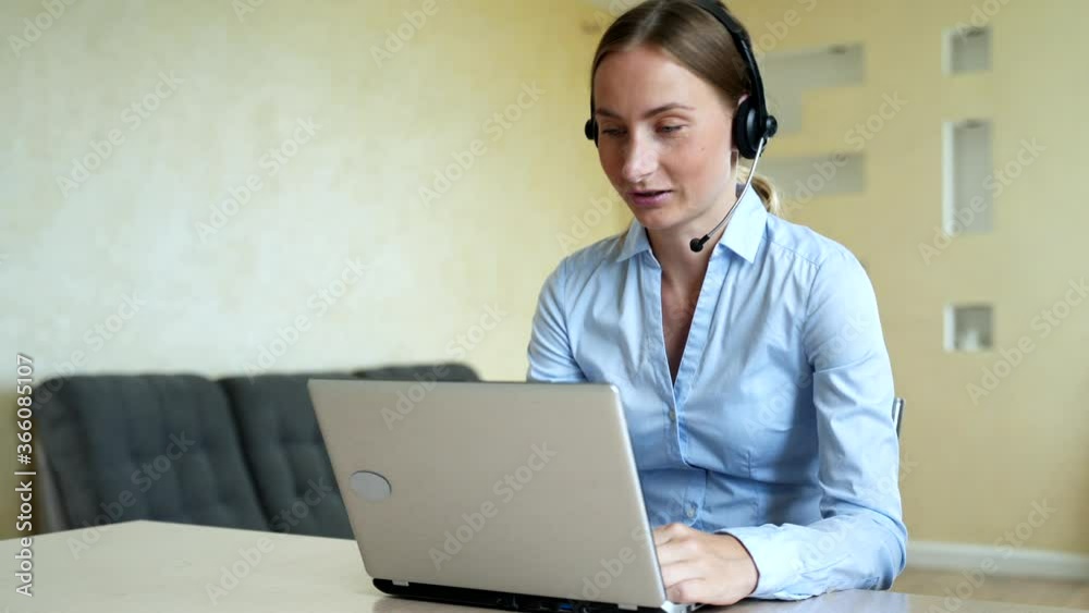 Woman wear headset communicating by conference call speak looking at computer at home office, video chat job interview Woman wear headset communicating by conference call speak looking at computer at home office, video chat job interview