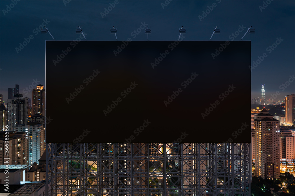 Blank black road billboard with Kuala Lumpur cityscape background at night time. Street advertising poster, mock up, 3D rendering. Front view. Concept of marketing to promote or sell idea or product.