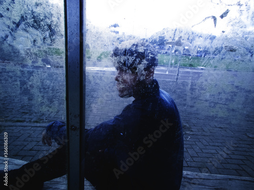 Man sitting behind a blurred glass - introvert man - phobia social - depressive man