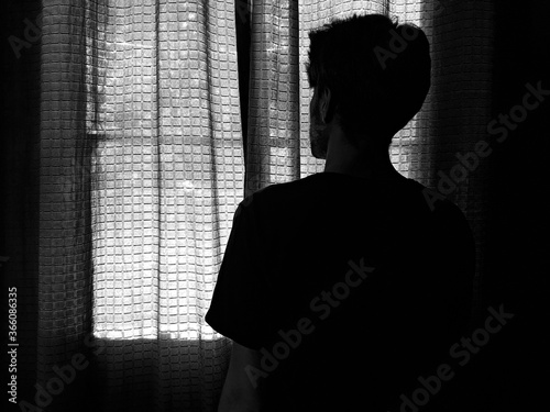 man alone looking through the brown curtain - depressive loneliness -  closed window - hiding from the world - dark  - out window 