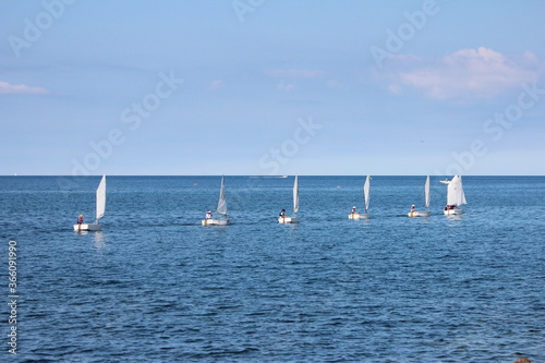 Civitavecchia,Italy -July 18,2020 : Sailboat instruction,The row of sailboat students are practice sailing near the A seaport on the Tyrrhenian Sea.Also have guideline and guarding boat,italy summer