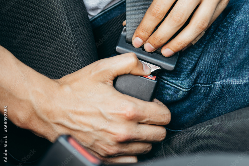 Men's hand fastens the seat belt of the car