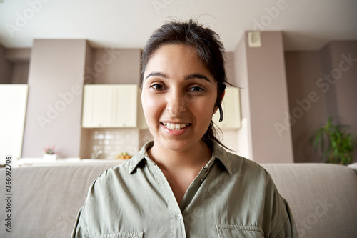 Smiling indian woman online teacher, sales agent, remote tutor or call center operator wearing headset look at webcam zoom conference video call at home office. Headshot portrait. Webcamera view.