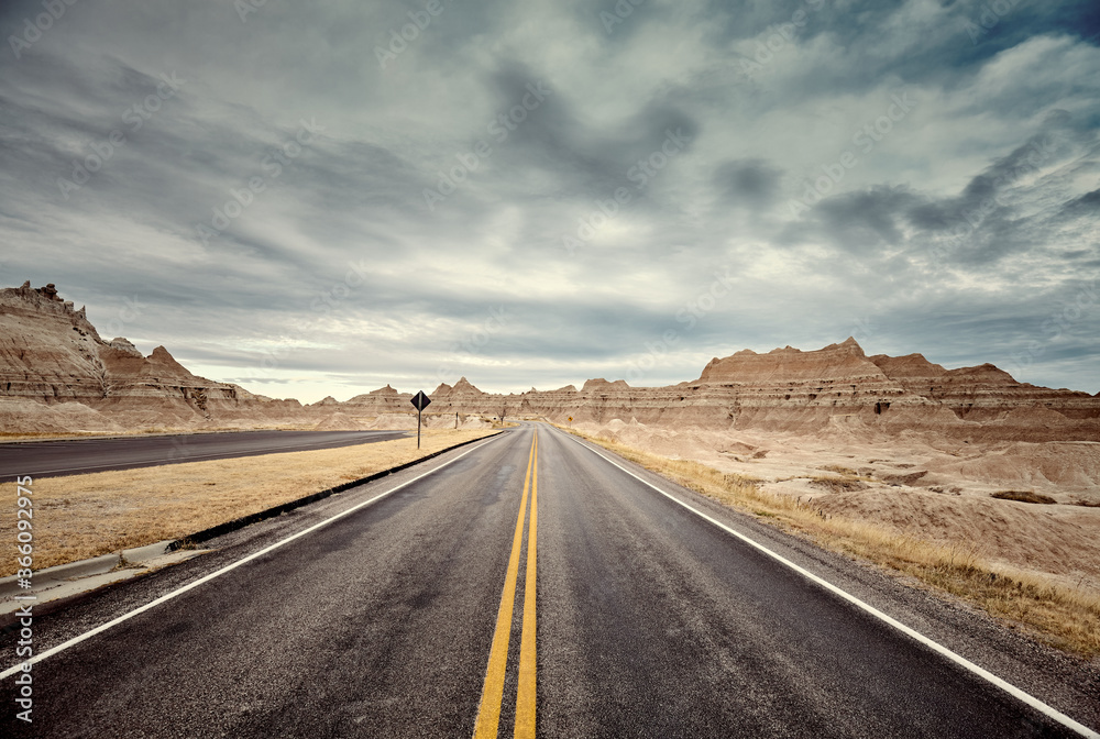Scenic road in Badlands National Park, color toning applied, travel concept, USA.