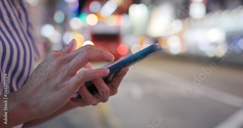 Woman use of mobile phone in the street at night