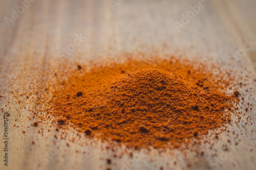 Heap of orange paprika powder on a wooden surface
