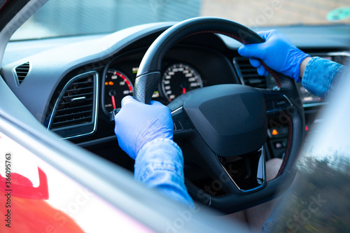 Close up of man with gloves taking the wheel of the car. COVID-19.