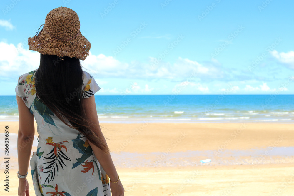 Outdoor summer portrait of young pretty woman looking to the ocean at tropical beach, enjoy her freedom and fresh air, wearing stylish hat and clothes on Vacation.