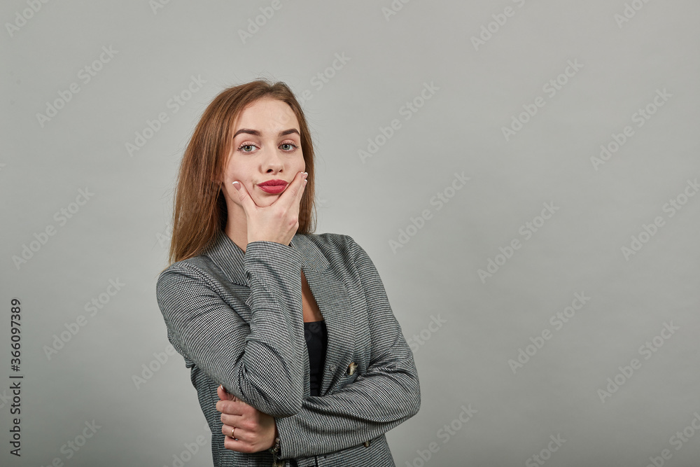 Hand on chin thinking about question, pensive expression. Doubt. Thoughtful face. Using that incredibly sharp business mind. Young attractive woman, dressed gray jacket, with green eyes, light brown Hand on chin thinking about question, pensive expression. Doubt. Thoughtful face. Using that incredibly sharp business mind. Young attractive woman, dressed gray jacket, with green eyes, light brown