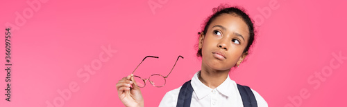 pensive african american schoolgirl with glasses isolated on pink, panoramic shot
