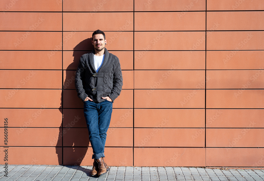 Front view of a fashionable young man standing against orange wall Front view of a fashionable young man standing against orange wall