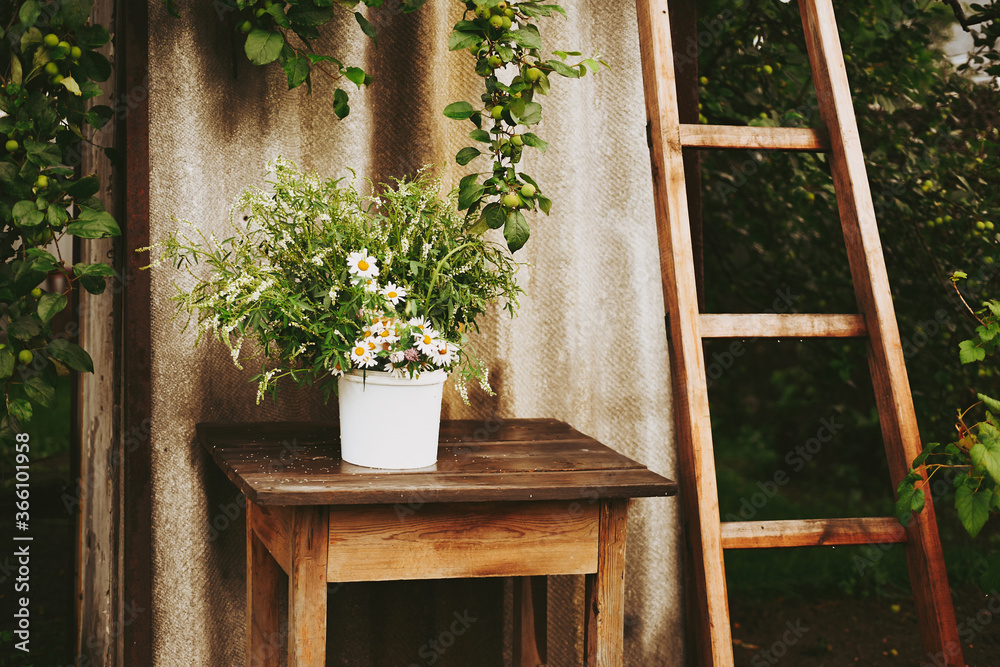 A bouquet of wildflowers and chamomiles on a wooden table. Flowers on a wooden table, rustic bouquet Authentic style A bouquet of wildflowers and chamomiles on a wooden table. Flowers on a wooden table, rustic bouquet Authentic style