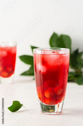 Summer delicious refreshing cherry compote with pulp and with ice in glasses on a white background