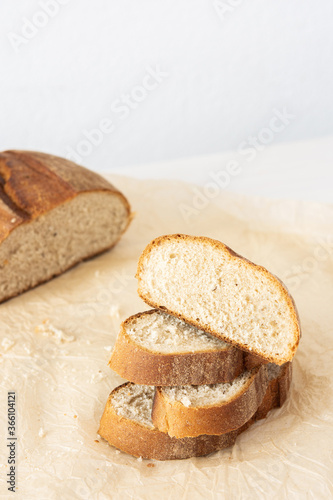 Loaf of homemade bread with sliced bread from wheat and seeds on parchment paper