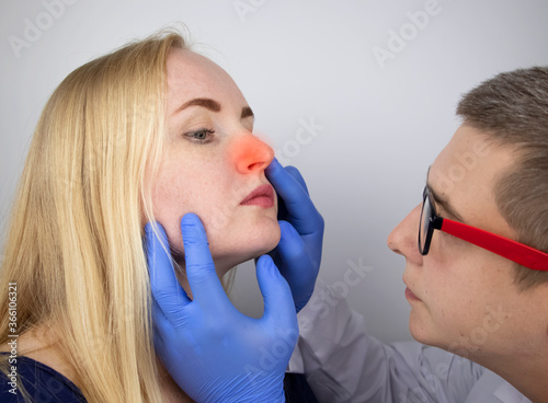 The otolaryngologist examines the girl's nasal passages. Painful sensations in the nose, polyps, adenoids and shortness of breath. Fractures of the cartilage tissue of the nose photo