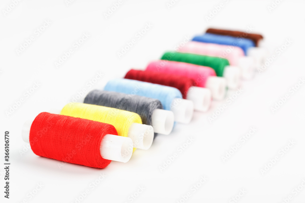 Sewing threads of different colors on reels on a white background. Free space, close-up. Isolate Sewing threads of different colors on reels on a white background. Free space, close-up. Isolate