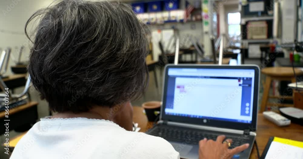 teacher works in empty classroom sweep around back