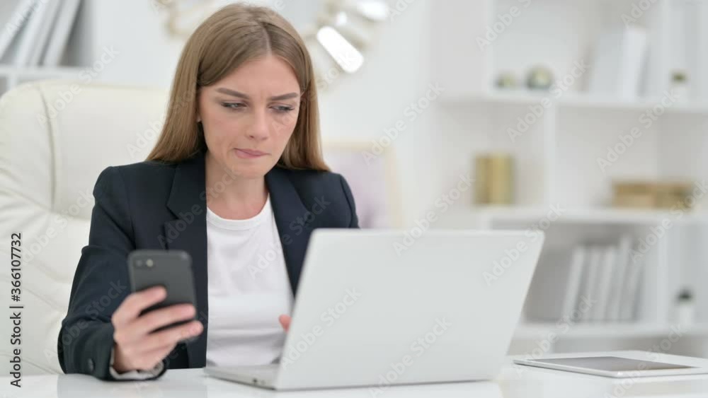 Busy Businesswoman using Smartphone and Laptop in Office Busy Businesswoman using Smartphone and Laptop in Office