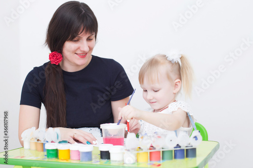 Young caucasian beautiful mother draws with her little daughter  preparing for school  copy space