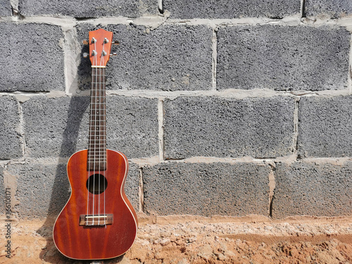 Ukulele on cement wall with space for text © phanlakhon