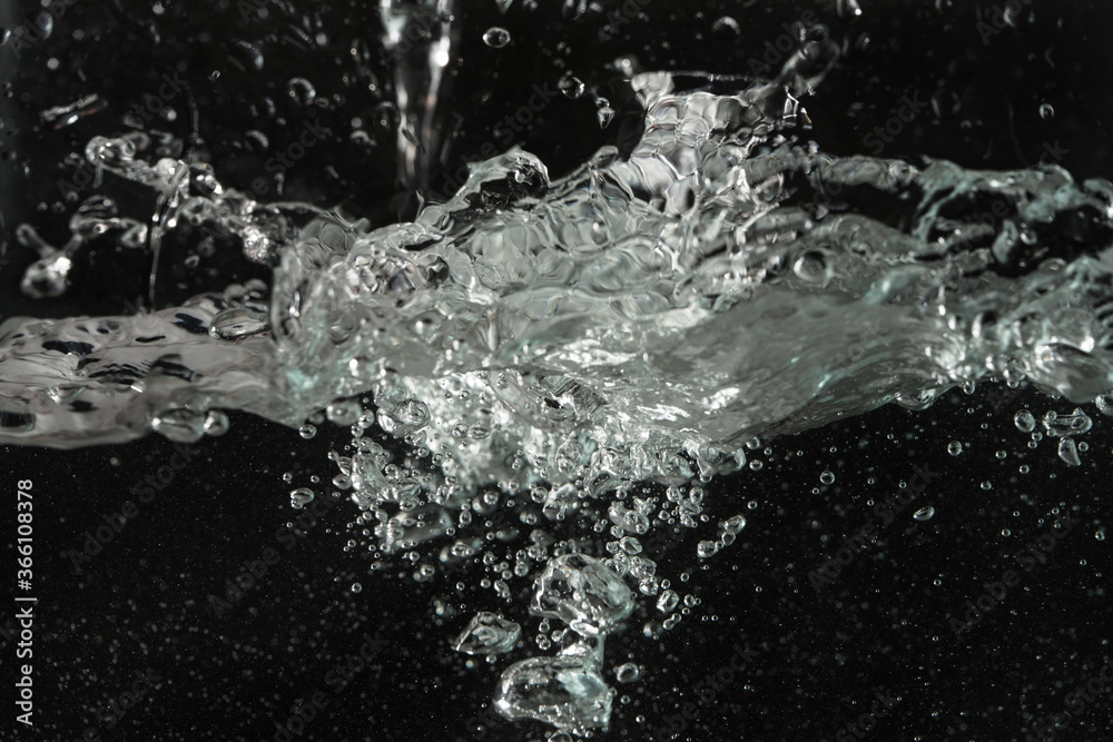 Water splashing as it's poured into aquarium tank, black background