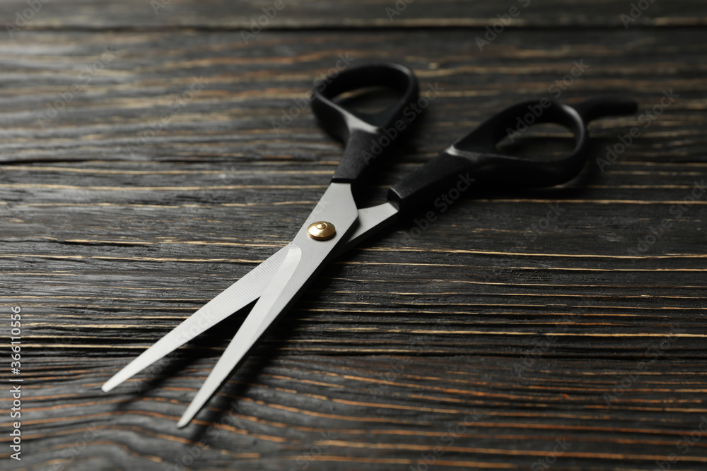 Black hairdresser scissors on wooden background, close up Black hairdresser scissors on wooden background, close up