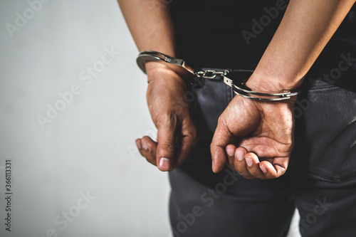 Prisoner male criminal standing in handcuffs with hands behind back.  photo