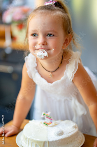 girl smeared  eating birthday cake with candles.