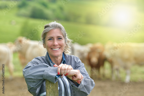 Portrait of a smiling cattlewoman standing beside her cows photo