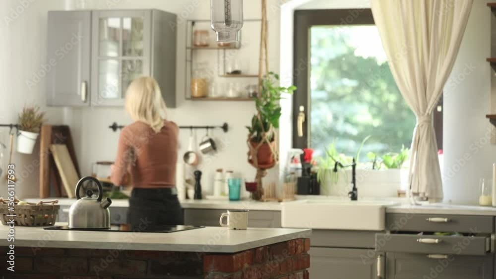 Blonde mother looking for something in a kitchen