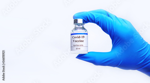 The doctor's hand is wearing blue gloves, holding the vaccine,Experimental vaccine covid-19,Healthcare And Medical concept.