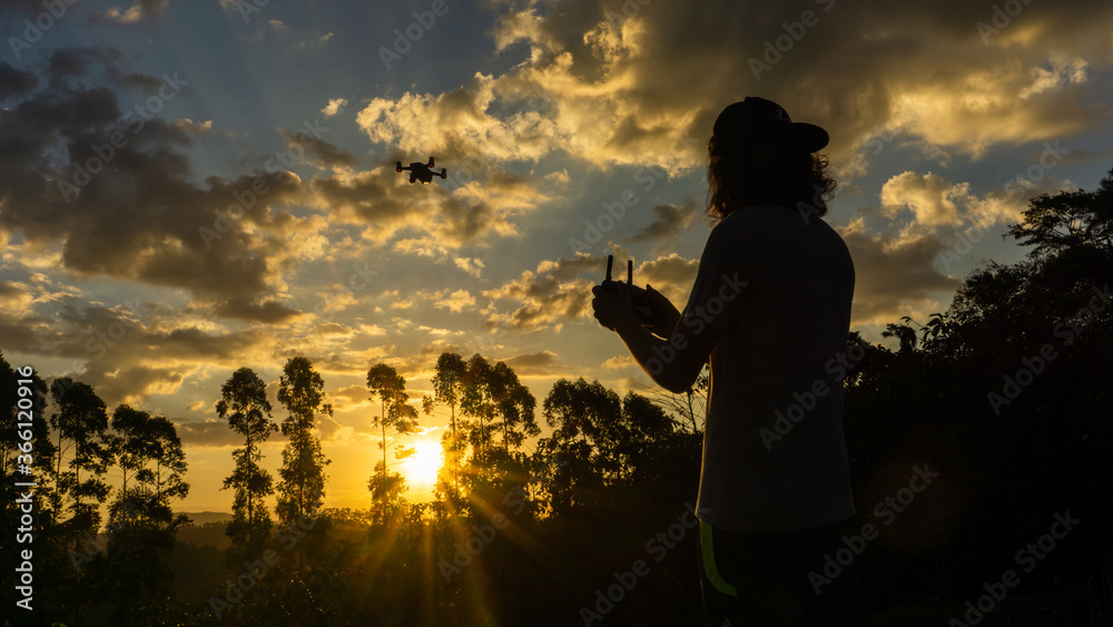 Fototapeta premium Boy flying a drone at sunset in brazil