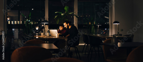 Confident male and female professionals working late together at creative office photo