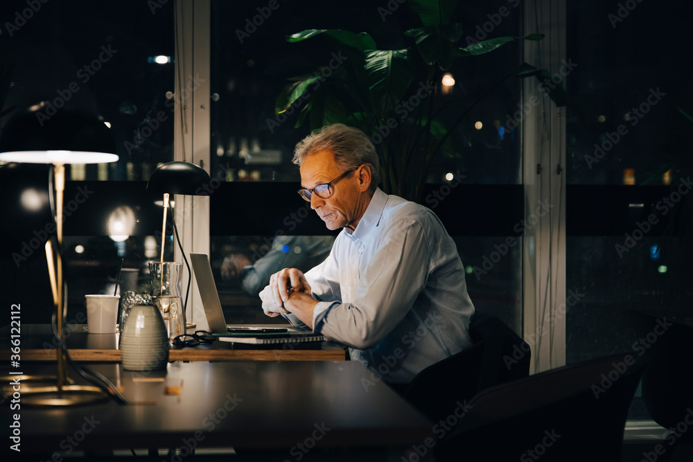 Dedicated senior male professional working late at creative workplace Dedicated senior male professional working late at creative workplace