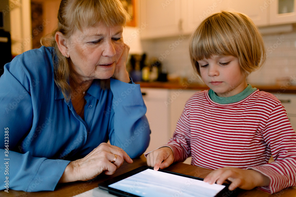 Senior woman looking at grandson using digital tablet Senior woman looking at grandson using digital tablet