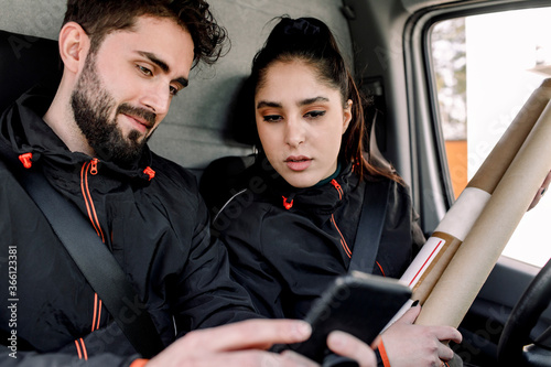 Young delivery man and woman using mobile phone in truck photo