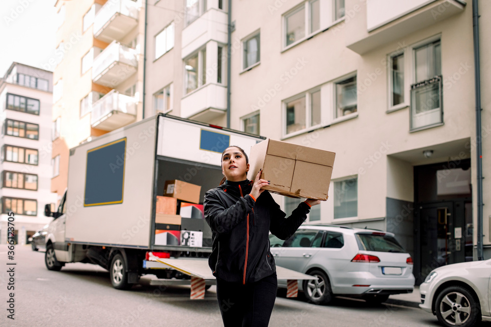 Young delivery woman carrying box on street Young delivery woman carrying box on street