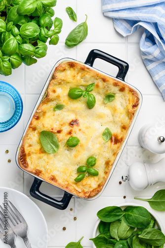 Lasagna with spinach and ricotta in a blue ceramic mold on a white background. Traditional italian dish. Top view