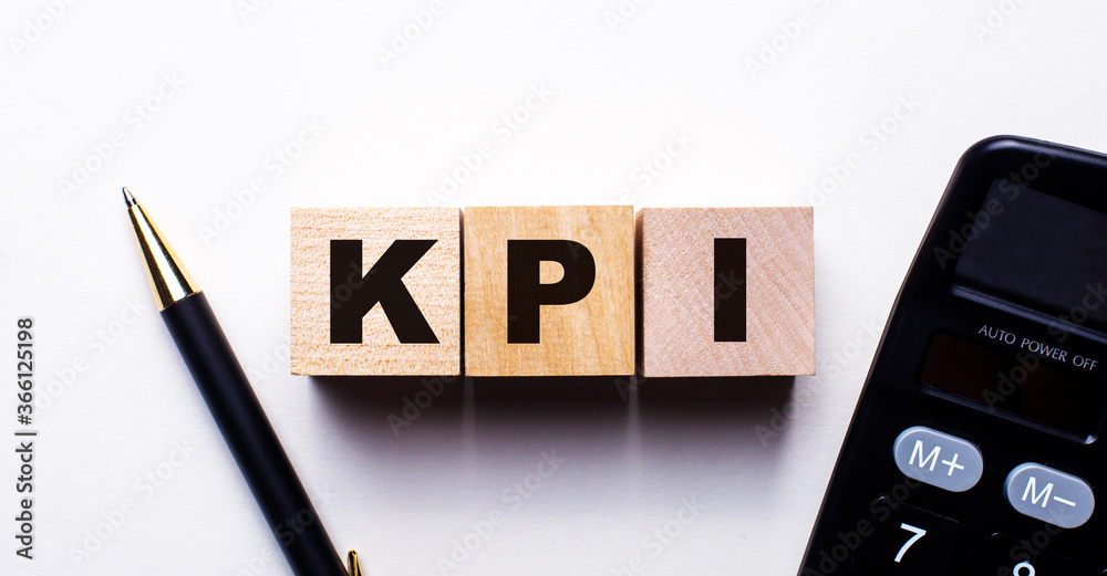 KPI is written on wooden cubes between a pen and a calculator on a light background. Business concept KPI is written on wooden cubes between a pen and a calculator on a light background. Business concept