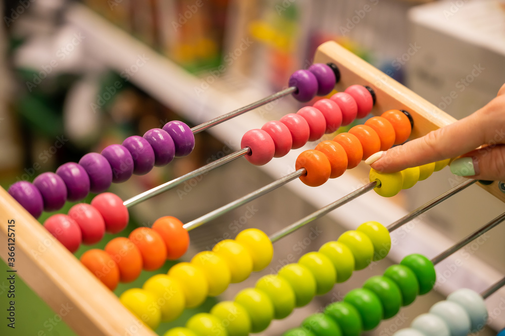 Closeup female hand calculating with balls on wooden rainbow abacus for number calculation. The concept of learning arithmetic for preschoolers. Closeup female hand calculating with balls on wooden rainbow abacus for number calculation. The concept of learning arithmetic for preschoolers.