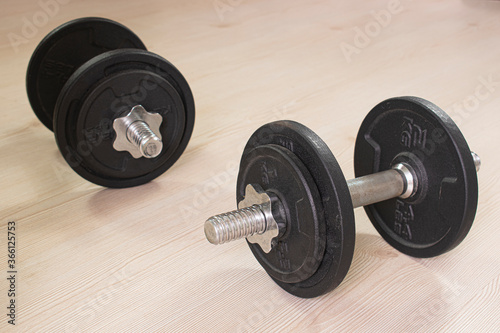 Dumbbells on wooden parquet floor. Sports concept photo at home