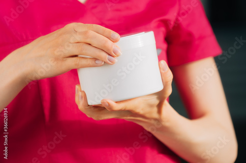 closeup young female hands doctor of a woman holding a jar of cream