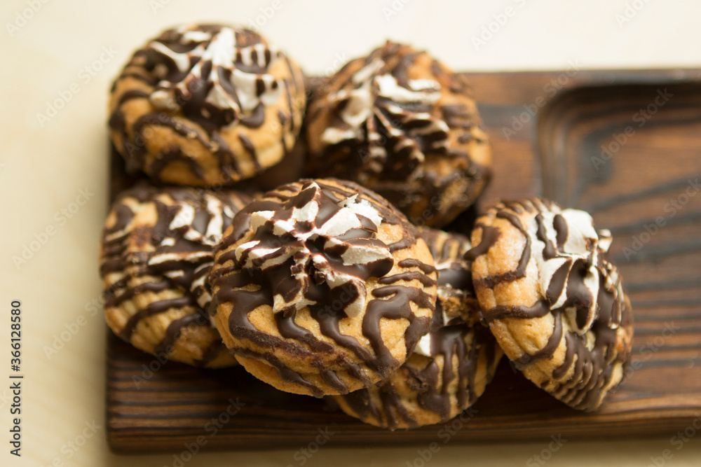 Sandy chocolate unusual striped cookies with marshmallows on a wooden plate tray. Cookies decorated with chocolate. Sandy chocolate unusual striped cookies with marshmallows on a wooden plate tray. Cookies decorated with chocolate.