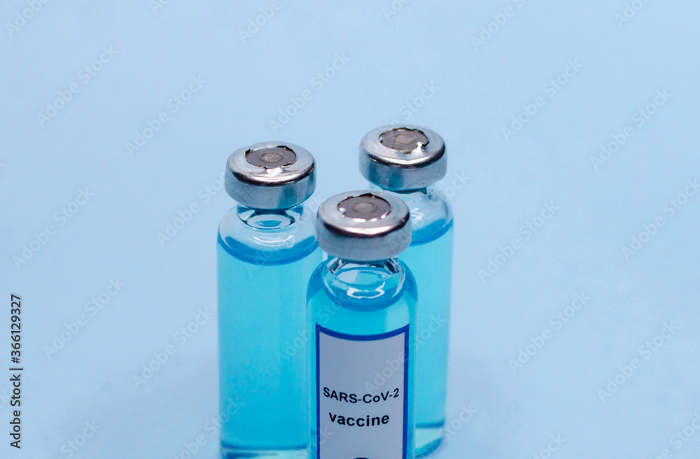 Three glass bottles with a vaccine on a blue background. Three glass bottles with a vaccine on a blue background.