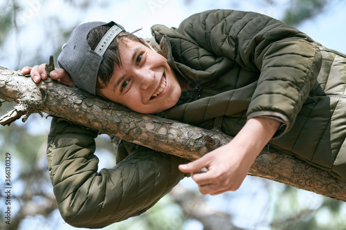 Tablou pe pânză teenage boy poses on a tree, lying on a big branch and dreaming