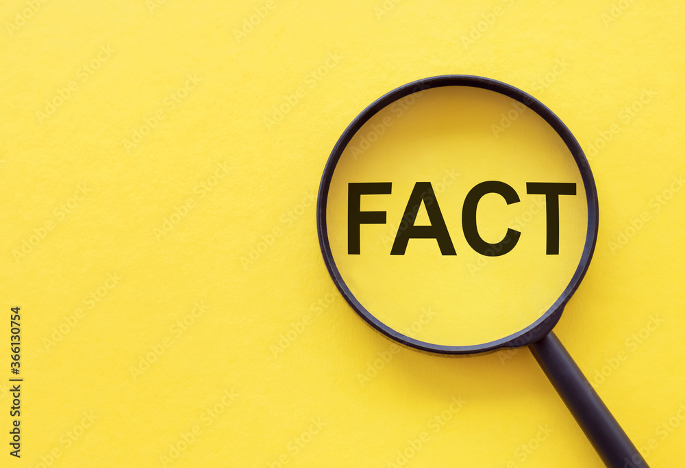 Fact - Word Through Magnifying Glass on yellow table Fact - Word Through Magnifying Glass on yellow table